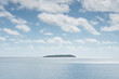 © Tetra Images - White puffy clouds over sea with small island