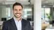 © halwaastudio - Cheerful young businessman with a confident smile looking at the camera in a bright office.
