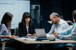 © Suteren Studio - Business executives and assistants brainstorming investment risk evaluation in corporate boardroom