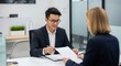 © An - Two business professionals discussing a document in an office setting.