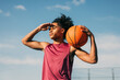 © ADDICTIVE STOCK - Young athlete holding basketball under blue sky