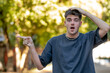 © carballo - young man in his 20s on the street pointing with a surprised expression