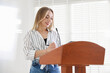 © New Africa - Woman giving public speech with microphone at lectern indoors