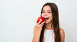 © Violet - Young woman smiling while holding a red apple in bright setting