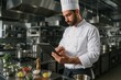 © Jelena - Professional chef utilizing tablet technology for digital menu planning and inventory management in modern restaurant kitchen