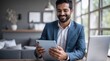 © VistaVisions - Smiling indian businessman in suit working on tablet and smile. Entrepreneurship professional career concept