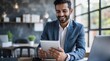 © VistaVisions - Smiling indian businessman in suit working on tablet and smile. Entrepreneurship professional career concept