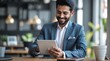© VistaVisions - Smiling indian businessman in suit working on tablet and smile. Entrepreneurship professional career concept