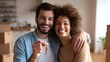 © Jittapon - A joyful couple enthusiastically celebrating their new home purchase and upcoming relocation holding a house key and smiling together in a contemporary living room setting