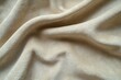 © Meenaxi - A close up shot of a soft beige fleece blanket with folds and subtle shadows in the light