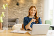 © Westend61 - Businesswoman smiling while working on a laptop in a modern office setting