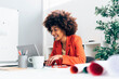 © Westend61 - Happy businesswoman with Afro hairstyle using laptop at desk in office