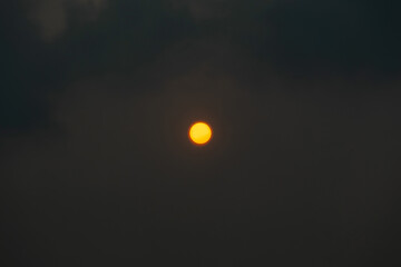 Wall Mural - red orange sun through the hazy clouds.