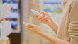 © Pavel - Customer selecting moisturizing SPF cream in a cosmetics store, comparing skincare and makeup products, reading ingredient labels. Close-up of woman's hands holding tubes. Concept of conscious choice