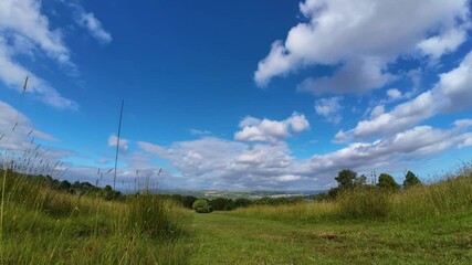 Wall Mural - fast timelapse over long grass field on wide angle lens with clouds moving quickly and fading as the