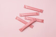 © zhennyzhenny - Pink sachets stick packs with copy space on matching pink background. Clean aesthetic for branding.
