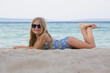 © triocean - Adorable little girl in blue swimwear and black sunglasses on the sand beach