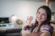 © Migma_Agency - Young woman waving hand while making video call at home