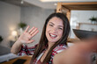 © Migma_Agency - Cheerful young woman waving at the camera during a video call