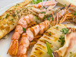 © HelgaQ - Grilled seafood platter with shrimp, fish, and calamari garnished with herbs on a plate