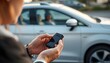 © Tahira - Man using a car key fob to remotely control his silver vehicle in an outdoor setting during the day