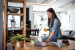 © Migma_Agency - Young businesswoman working from home, drinking orange juice and using laptop