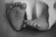 © Jurii - A tender black and white close-up of a newborn baby's tiny feet in loving hands. Symbolizing new life, parental love and pure innocence, selective focus.