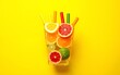 © ming - Creative concept of citrus juice, smoothie, summer drinks. Slices of orange, grapefruit, lemon and lime are folded in the shape of glass on yellow background. Top - red, yellow, green, orange tubules.