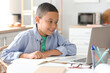 © Pixel-Shot - Little African-American boy studying computer sciences online in kitchen