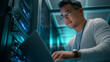 © Andrii - Asian IT Technician Working with Laptop in a Server Rack at a Modern Data Center. Ideal for showcasing cloud computing, network security, or tech support services.
