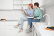 © Pixel-Shot - Young women with furniture assembling instructions sitting on table in kitchen
