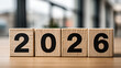 © Vitalii - Wooden blocks with the number 2026 arranged in a row, representing the upcoming new year with a modern business background