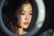 © MONY STUDIO - Elegant portrait of a young woman applying blush in a softly lit setting, highlighting her natural beauty and radiant complexion.