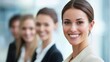 © Mey - A smiling businesswoman with a confident expression, standing in front of a blurred background of other businesswomen.