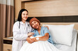 © artitwpd - Smiling female doctor comforting a happy female cancer patient in bed during recovery. Concept of empathy, support, and healing in hospital care, with a focus on trust and professional treatment.