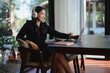 © Parichat - Smiling businesswoman working remotely during christmas holidays using headphones and laptop