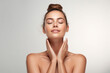 © Golapi - A young woman with her eyes closed and hands on her neck in a skincare focused portrait
