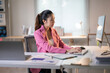 © Wasana - A woman in a pink jacket is typing on a computer