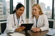 © Zakir - Two female doctors in white coats review medical data on a tablet in a modern office with city view