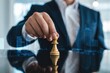 © Netsai - Businessman placing golden pawn on reflective surface, city skyline backdrop suggesting strategic planning.