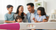 © oliamogdaleva - Positive pregnancy test with joyful, blurred large family in background, anticipating the arrival of another sibling.