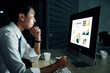 © AU USAnakul - Professional man using stylus to review financial charts on computer in dark office. Late-night productivity concept for technology-driven business.