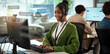 © Leny Studio - Cheerful customer support representative wearing headset is working at computer in modern office environment. background shows other team members collaborating in bright, open space