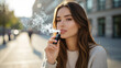 © DAYA-DAKSH - Young woman enjoys an electronic cigarette in a candid outdoor scene with city backdrop on a sunny afternoon.