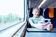 © Iryna - Happy teen boy enjoying screen time on train journey