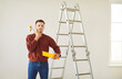 © Studio Romantic - Portrait of young man painter standing in new apartment holding paint roller in hands dissatisfied with the repair. Male person feeling frustrated to have much work. Renovation concept.