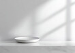 © siraj - A clean white bowl rests on a marble surface with soft window light and shadow patterns