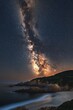 © Milana - Vibrant Milky Way galaxy shining brightly over rocky coastline and calm ocean under a starry night sky