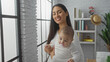 © Krakenimages.com - Woman smiling holding baby in cozy living room with white brick wall and bookshelves, sunlight streaming through big windows, portraying warmth, love, and family bonding indoors.