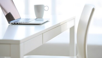 Silver laptop and white mug on a clean white desk with a chair computer technology